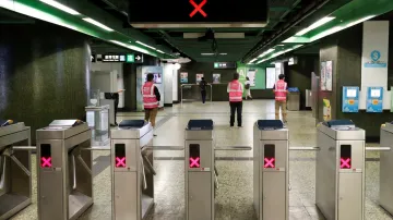 Zaměstnanci stanice Fortress Hill stojí před turnikety, protože stanice je dočasně uzavřena kvůli přerušení služeb železniční dopravy MHD protestujícími v Hongkongu.