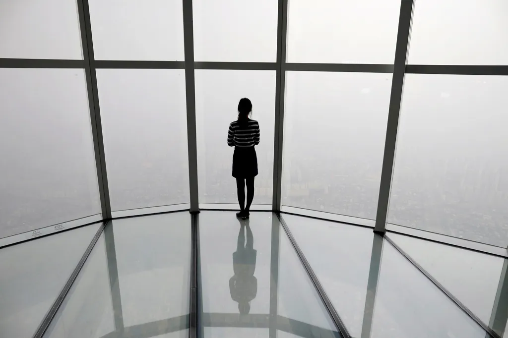 Žena u stěny mrakodrapu v jihokorejském Soulu během smogové situace