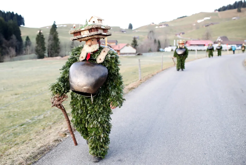 Muži oblečení v kostýmu postaviček "Chlaeuse"putují vesnicí Urnaesch ve Švýcarsku