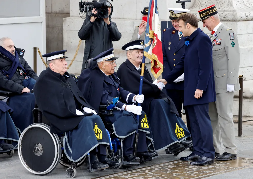 Francouzský prezident Emmanuel Macron se zdraví s válečnými veterány při ceremonii u Vítězného oblouku v Paříži.