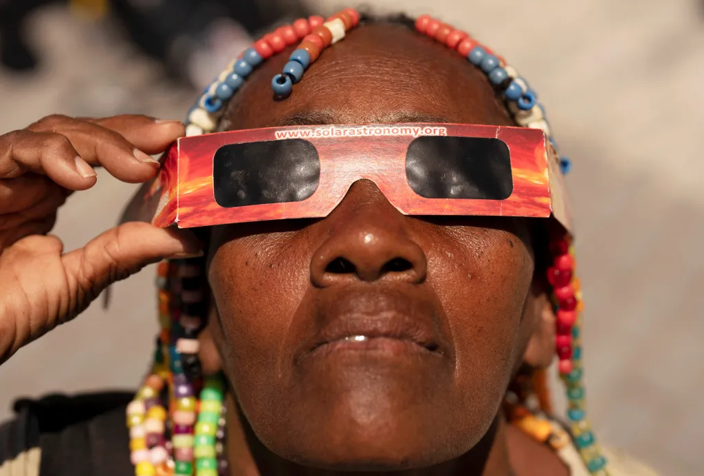 Kadeřnice, která si říká „Sladká Irma“, používá speciální ochranné brýle při pozorování částečného zatmění Slunce v Havaně na Kubě