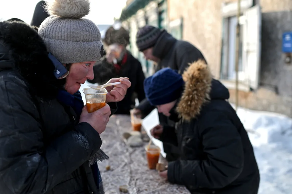 Žena bez domova Ljuda obědvá horkou kuřecí polévku. Tu každý týden vaří před recyklačním centrem v Omsku