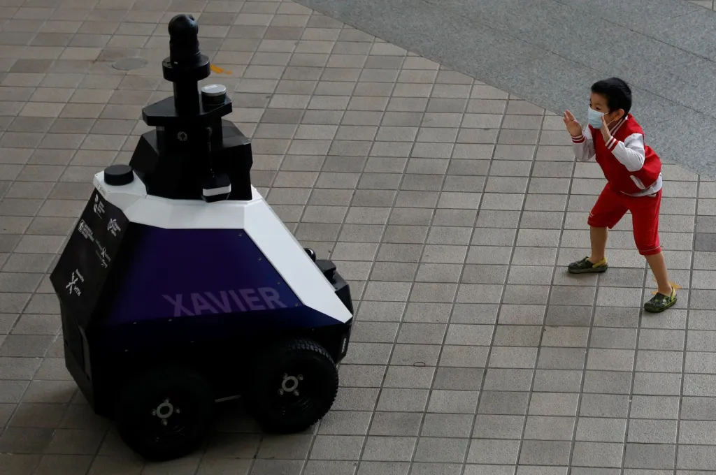 Dítě pronásleduje autonomního robota Xaviera, který během třítýdenního zkušebního provozu hlídkuje a monitoruje „nežádoucí sociální chování“ obyvatel Singapuru