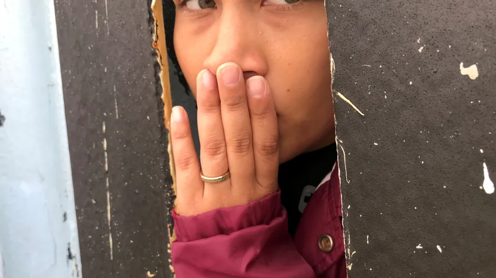 Žena u zdi mezi Mexikem a USA dívající se z Tijuany na druhou stranu hranice