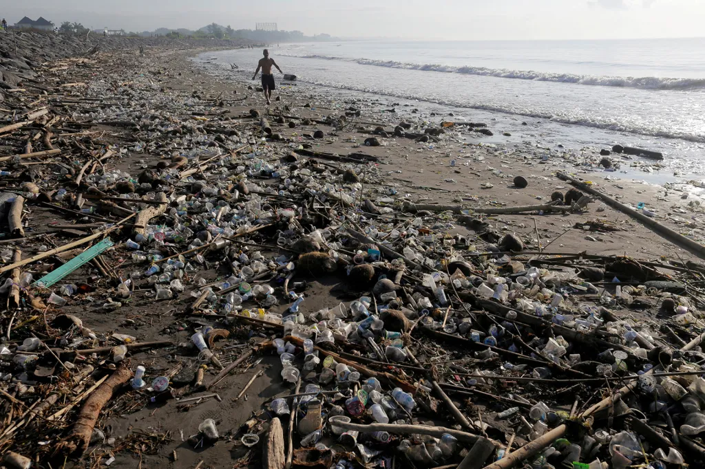 Domorodec kráčí po pláži Matahari Terbit v indonéském Bali. Pláž je permanentně pokryta plastovým odpadem, který sem naplavují přílivové vlny.