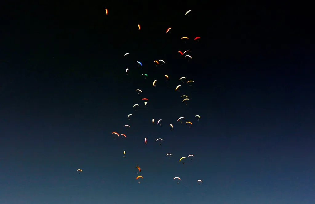 Paraglidisté se vznášejí z nebe v Krusevu v Severní Makedonii během 16. světového šampionátu v paraglidingu