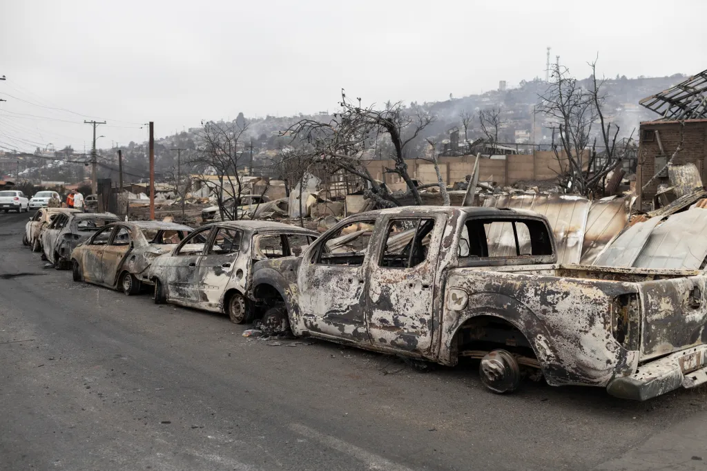 V ulicích po požáru zůstaly ohořelé vraky aut a vyhořelé domy