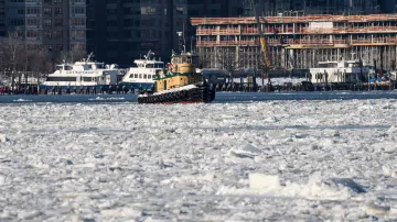 Loď pluje mezi ledovými krami na řece Hudson mezi New Jersey a New Yorkem