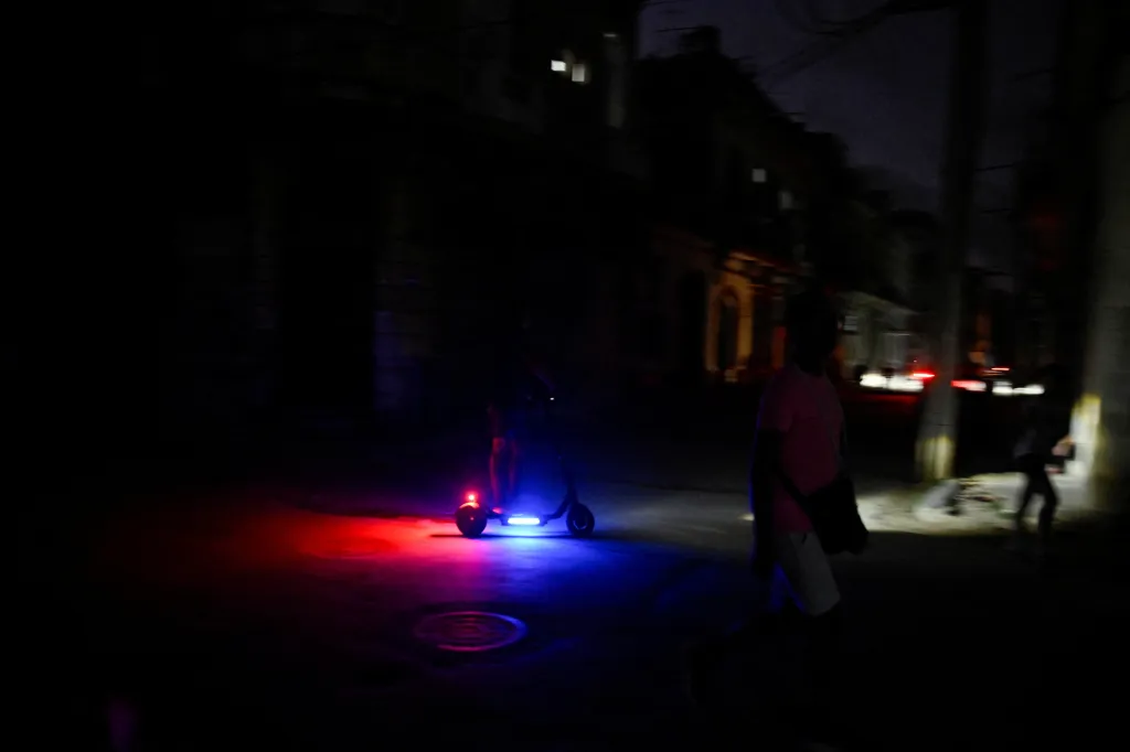 Osoba na koloběžce projíždí temnou Havanou