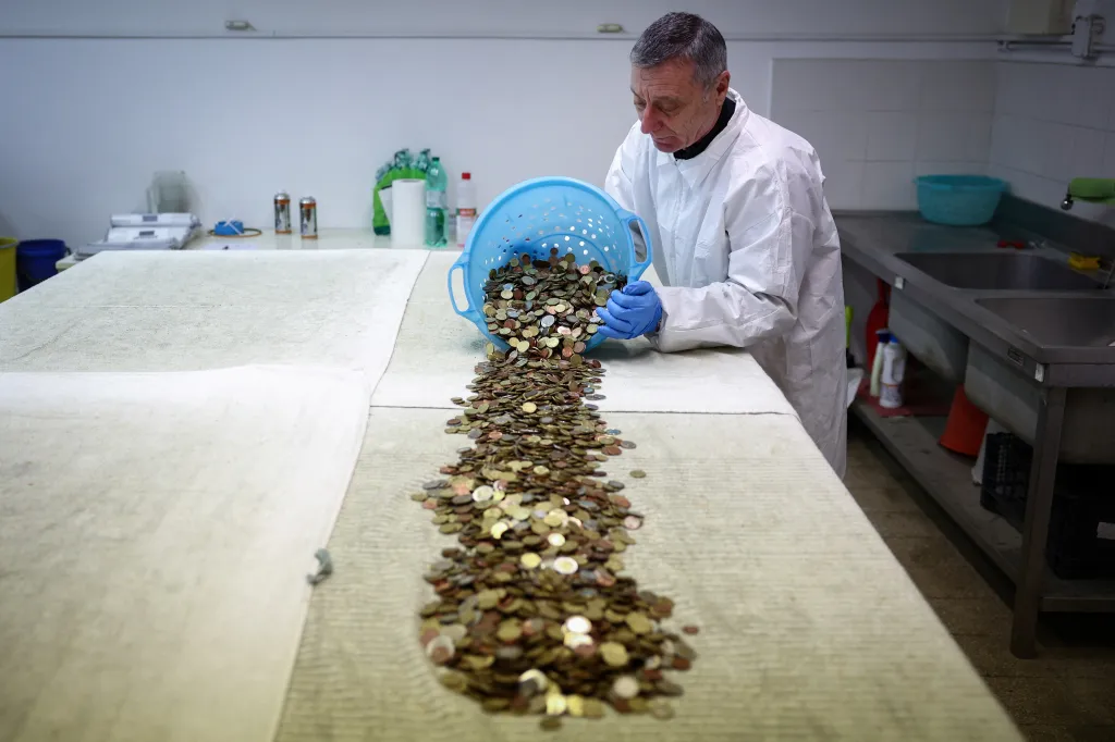 Dobrovolník Chiolini vykládá kbelík s mincemi. Obsah musí pečlivě třídit, protože kromě mincí ve fontáně už našli i šperky, zubní protézy, náboženské medailonky, a dokonce i pupeční šňůru
