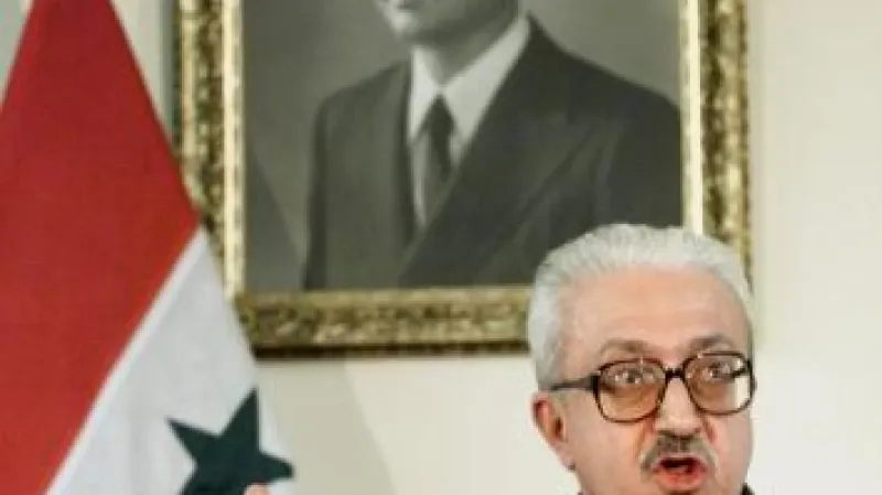 tárik Azíz před portrétem Saddáma Husajna