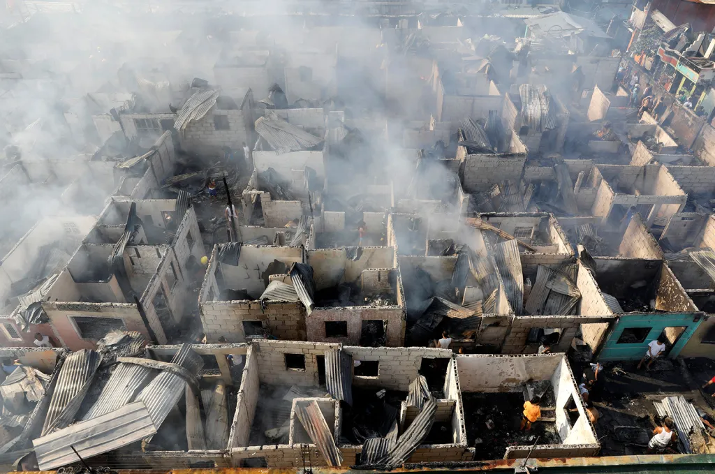 Oběti požáru prohlížejí zbytky svých domů, které byly zničeny ohněm ve filipínském Paranaque nedaleko Manily.