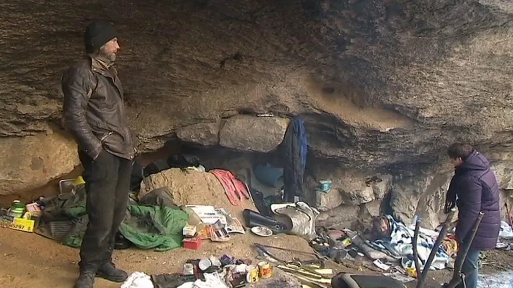 Lidé bez domova pod skalním převisem
