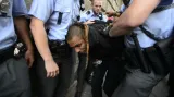Policisté odvádějí jednoho z účastníků happeningu squatterské iniciativy Obsaď a žij