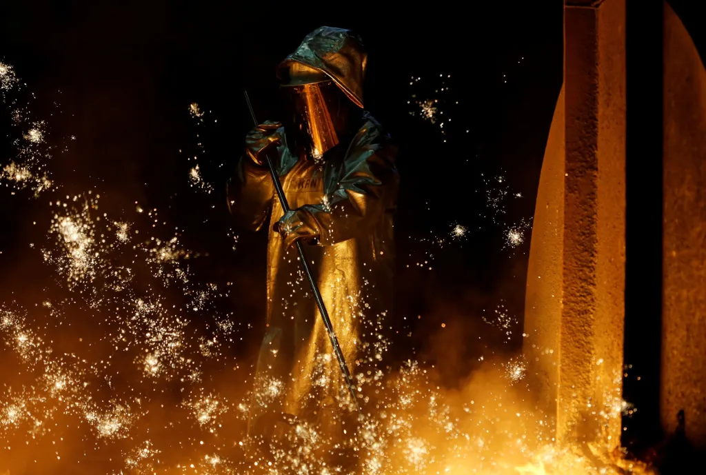 Pracovník vysoké pece odráží proud surového železa při výrobě oceli ve firmě ThyssenKrupp v Duisburgu v Německu