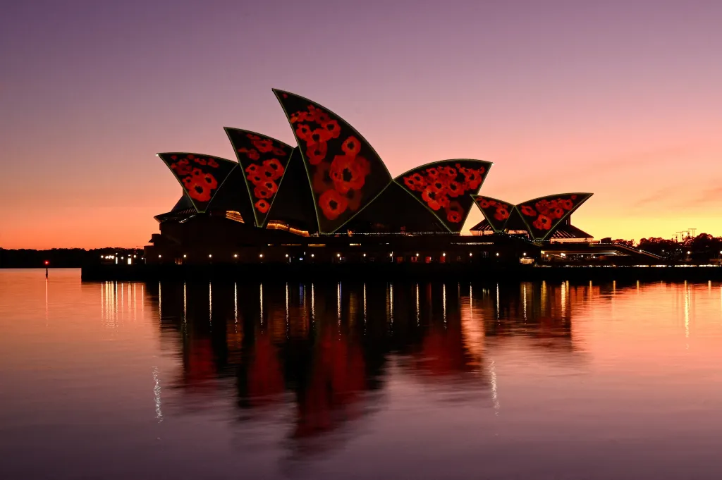 Průčelí střechy opery v Sydney jsou za rozbřesku Dne válečných veteránů osvětleny projekcí vlčích máků.