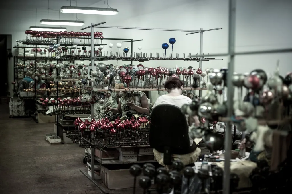 V místnosti, kde se baňky zdobí, vládne dobrá atmosféra. Ženy si při práci povídají a samotná scéna připomíná dobu, kdy babičky draly peří