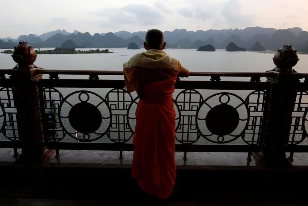 Buddhistický mnich se modlí u jezera během dne Vesak, každoroční oslavy narození Buddhy
