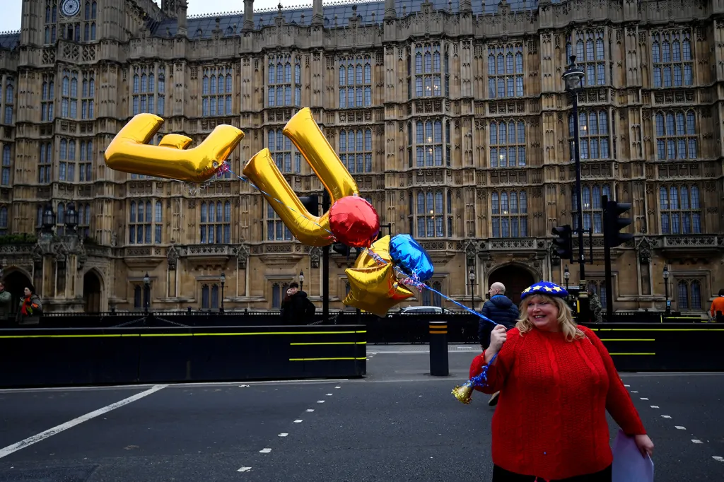 Demonstrant proti brexitu s balonky ve tvaru písmen „EU“ před budovou britského parlamentu v Londýně