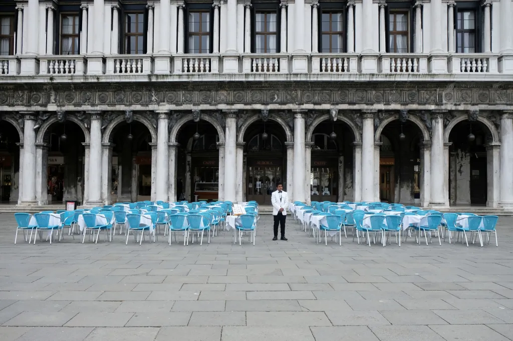 Číšník stojí u prázdných stolů před restaurací na náměstí Svatého Marka v Benátkách poté, co italská vláda přijala nařízení o nouzovém opatření během boje proti koronaviru