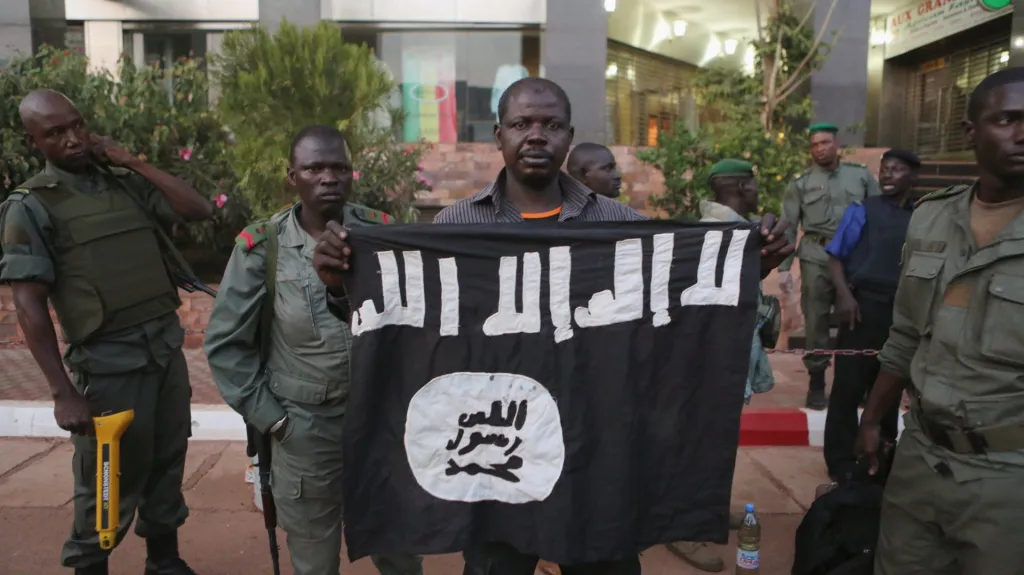 Malijské bezpečnostní síly prezentují džihádistickou vlajku, která patřila atentátníkům z hotelu Radisson