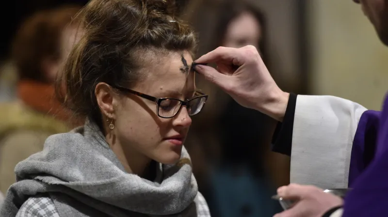 Kněz uděluje popelec účastnici mše na Popeleční středu v Olomouci