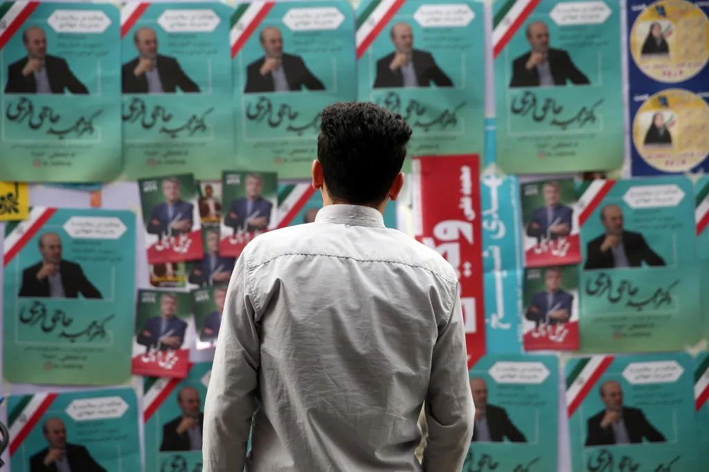 Muž z Teheránu si prohlíží kampaňové letáky pro parlamentní volby v Íránu