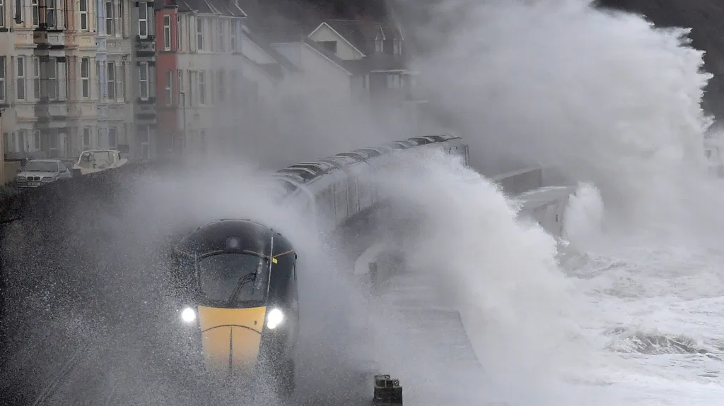 Velké vlny se tříští o vlak, který projíždí po pobřeží města Dawlish v jihovýchodní Británii