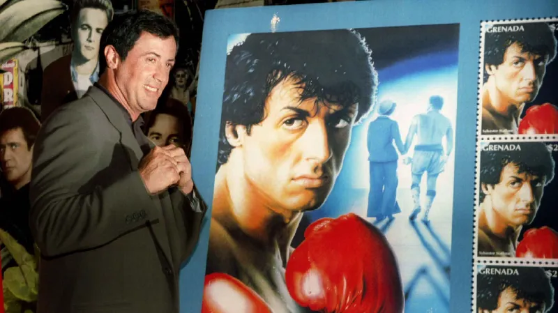 Sylvester Stallone pózuje vedle poštovní známky inspirované filmem Rocky (1996)