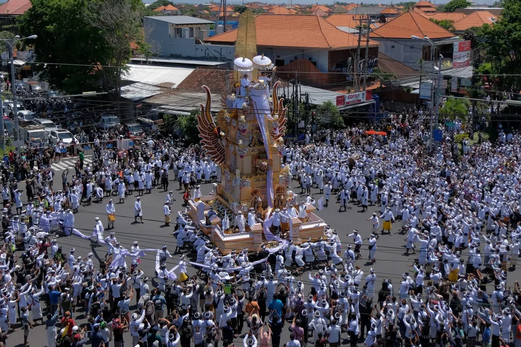 Lidé doprovázejí během smutečního obřadu šestnáct metrů vysokou kremační věž obsahující tělo významného hinduistického kněze v Denpasaru na Bali
