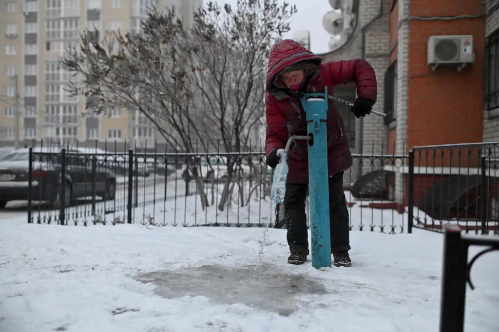 Ljusja Stěpanovová, čtyřicetičtyřletá žena bez domova, plní lahev vodou z veřejné pumpy