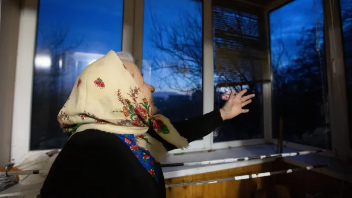 Obyvatelka Kyjeva ukazuje okna vyražená tlakovou vlnou po jednom z ruských útoků