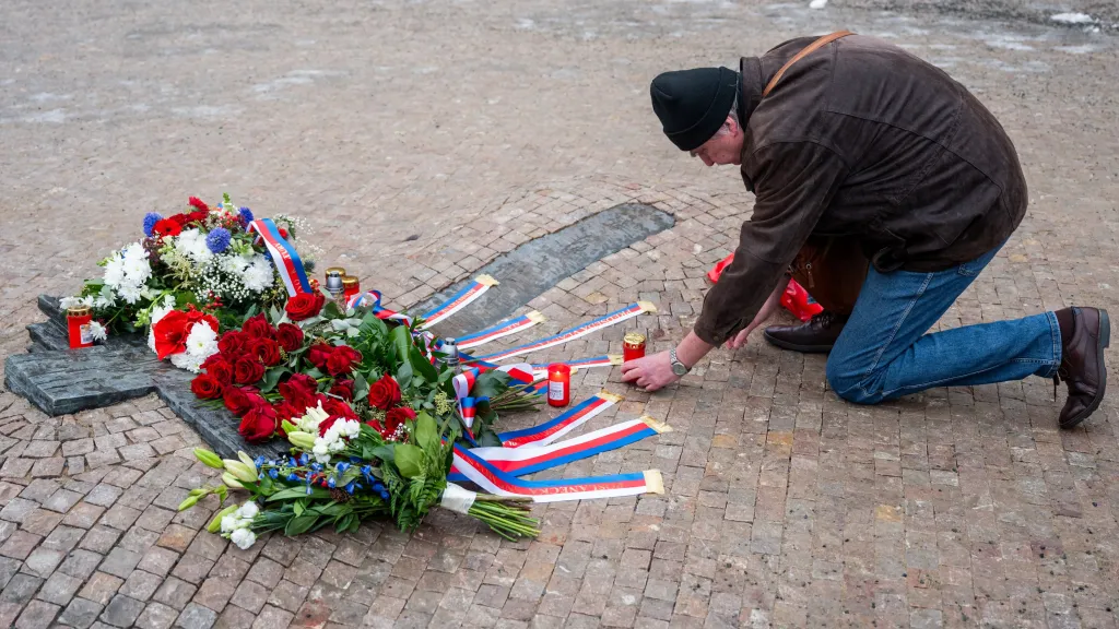 Muž pokládá svíčku u památníku studenta Jana Palacha