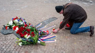 Muž pokládá svíčku u památníku studenta Jana Palacha