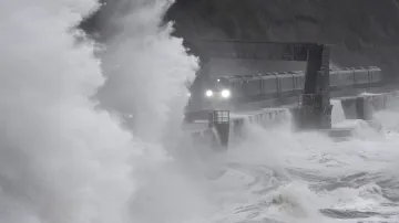 Velké vlny se tříští o vlak, který projíždí po pobřeží města Dawlish v jihovýchodní Británii