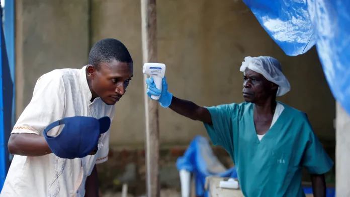 Zdravotník kontroluje teplotu jednomu z pacientů v konžském zdravotnickém centru