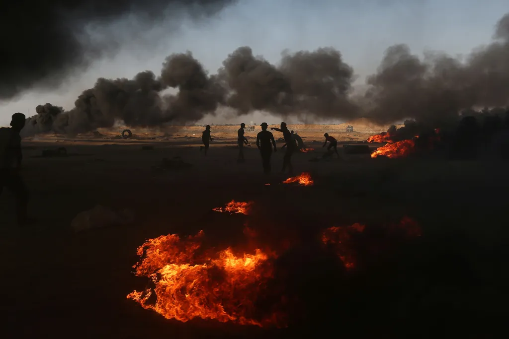 Palestinští demonstranti v oblacích hustého dýmu z hořících pneumatik během protestů na hranici Gazy a Izraele k výročí 70 let založení židovského státu a přesunutí americké ambasády z Tel Avivu do Jeruzaléma
