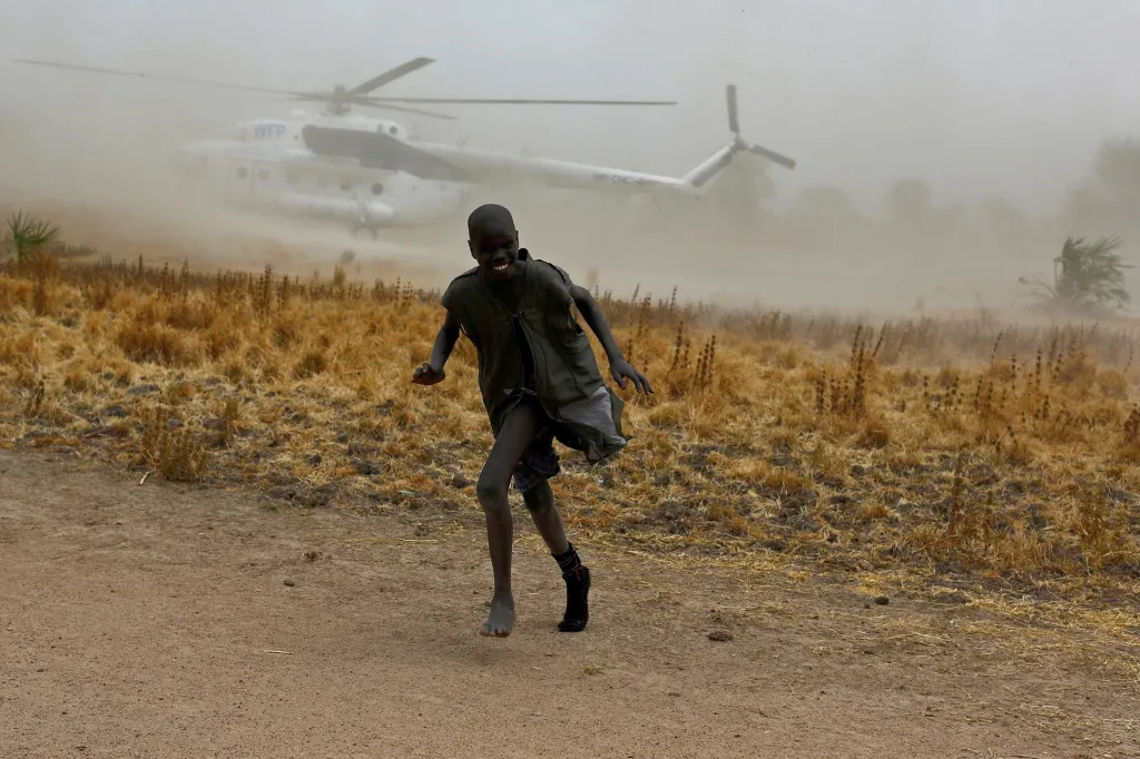 Chlapce ve vesnici Rubkuai v severní části Jižního Súdánu ochromil prach od přistávajícího vrtulníku, který přivezl potravinovou pomoc během hladomoru. Fotografie z 18. února 2017