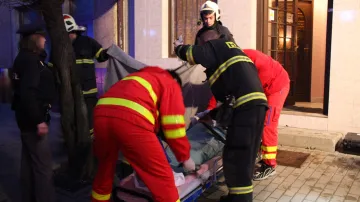 Záchranáři s hasiči nakládají popálenou seniorku
