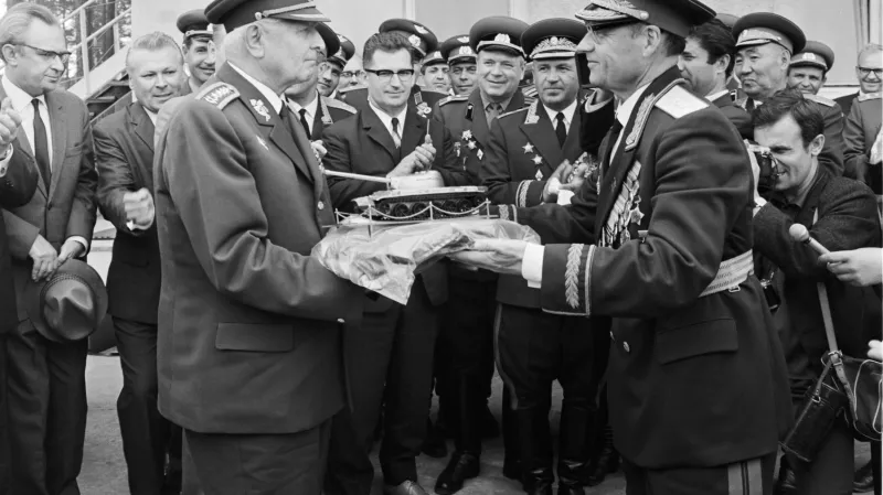 Dobový popisek ČTK z května 1969: Prezident republiky a vrchní velitel ozbrojených sil Ludvík Svoboda přebírá během návštěvy československých představitelů v Milovicích u Střední skupiny sovětských vojsk z rukou jejího velitele A. M. Majorova jako dar model tanku. V pozadí uprostřed tajemník ÚV KSČ Lubomír Štrougal.