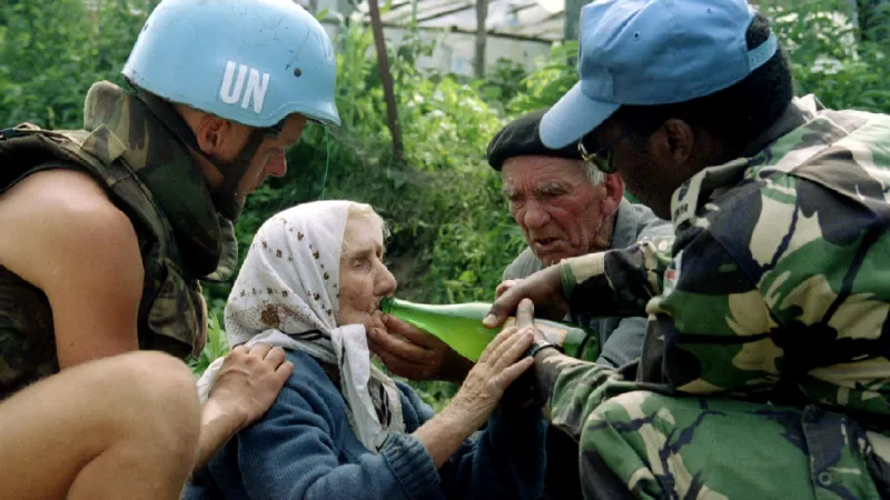 Vojáci mírových jednotek OSN pomáhají uprchlíkům, kterým se podařilo Srebrenici opustit (13. července 1995)