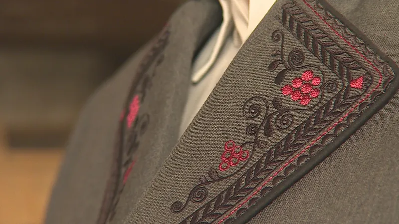 Vinařský kroj má na šedém podkladu výšivky hroznu révy vinné