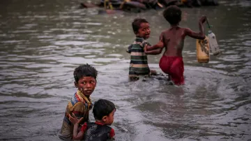 Rohingští sourozenci, kteří prchli před násilím v Myanmaru přes řeku Naf River do Bangladéše si pomáhají na posledních metrech strastiplné cesty