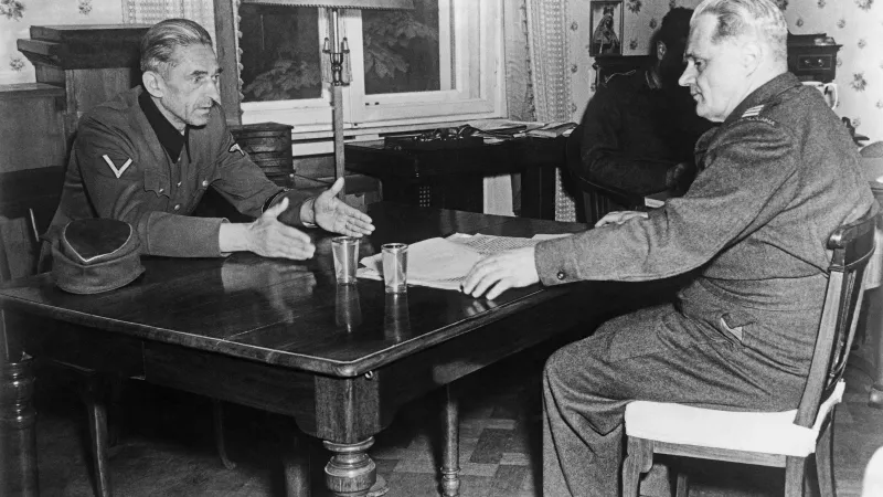 Karl Hermann Frank (vlevo) při prvním výslechu, za stolem uprostřed vyšetřovatel Bohuslav Ečer, zcela vpravo zapisovatel V. Fanderlík