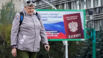 Žena prochází kolem billboardu s ruským pasem