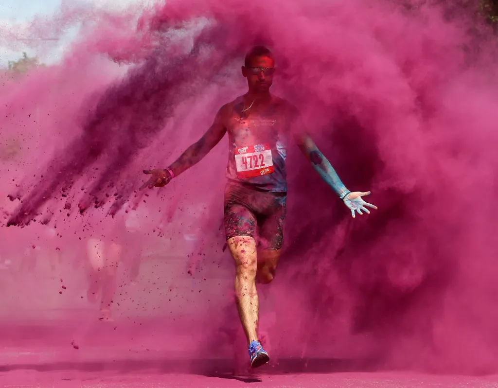 Závody, během kterých se sype na běžce barevný prášek, jsou v současnosti populární. Na fotografii sportovec dokončuje barevný závod Color Run v Moskvě