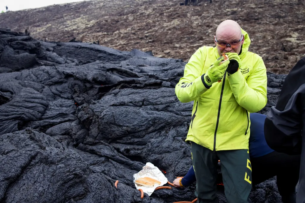 Jeden z turistů konzumuje tepelně upravené párky na chladnoucí lávě
