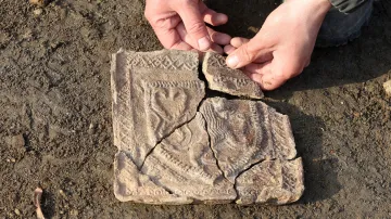 Archeolog Šimon Kochan ukazuje téměř kompletní kachel z gotických kamen zdobený reliéfem českého lva nalezený ve Velkém Meziříčí (18. března 2026)