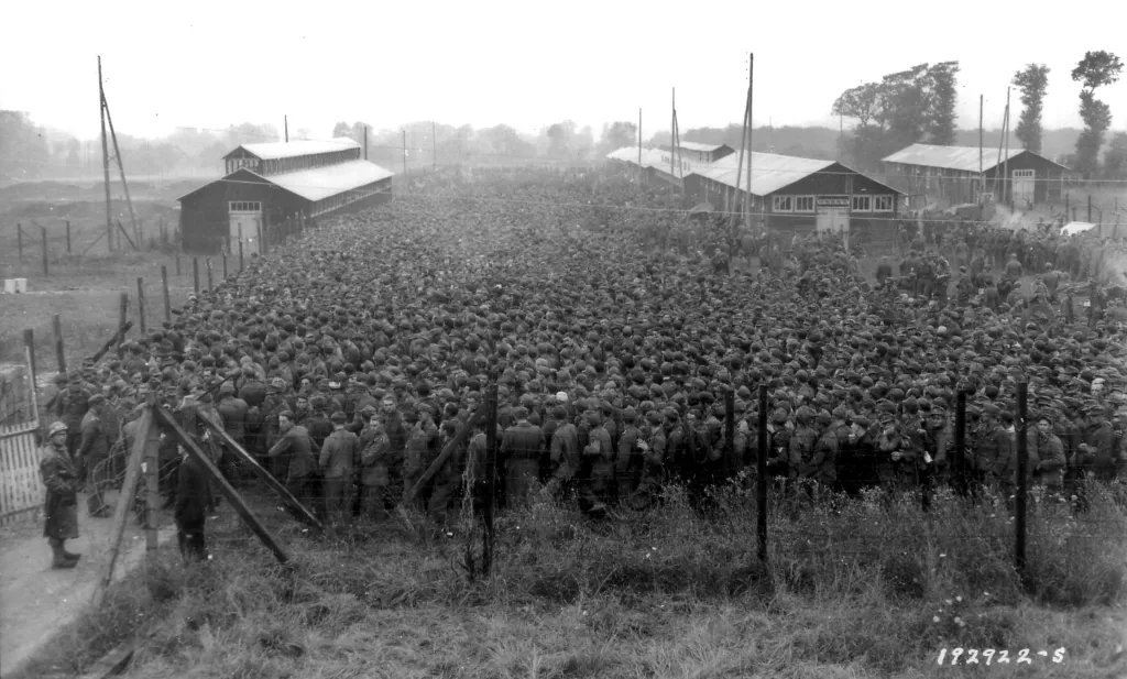 Na snímku z 21. června 1944 jsou němečtí váleční zajatci střežení americkými jednotkami v táboře v Nonant-le-Pin ve Francii