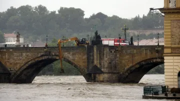 Bagr odklízí naplaveniny na uzavřeném Karlově mostě